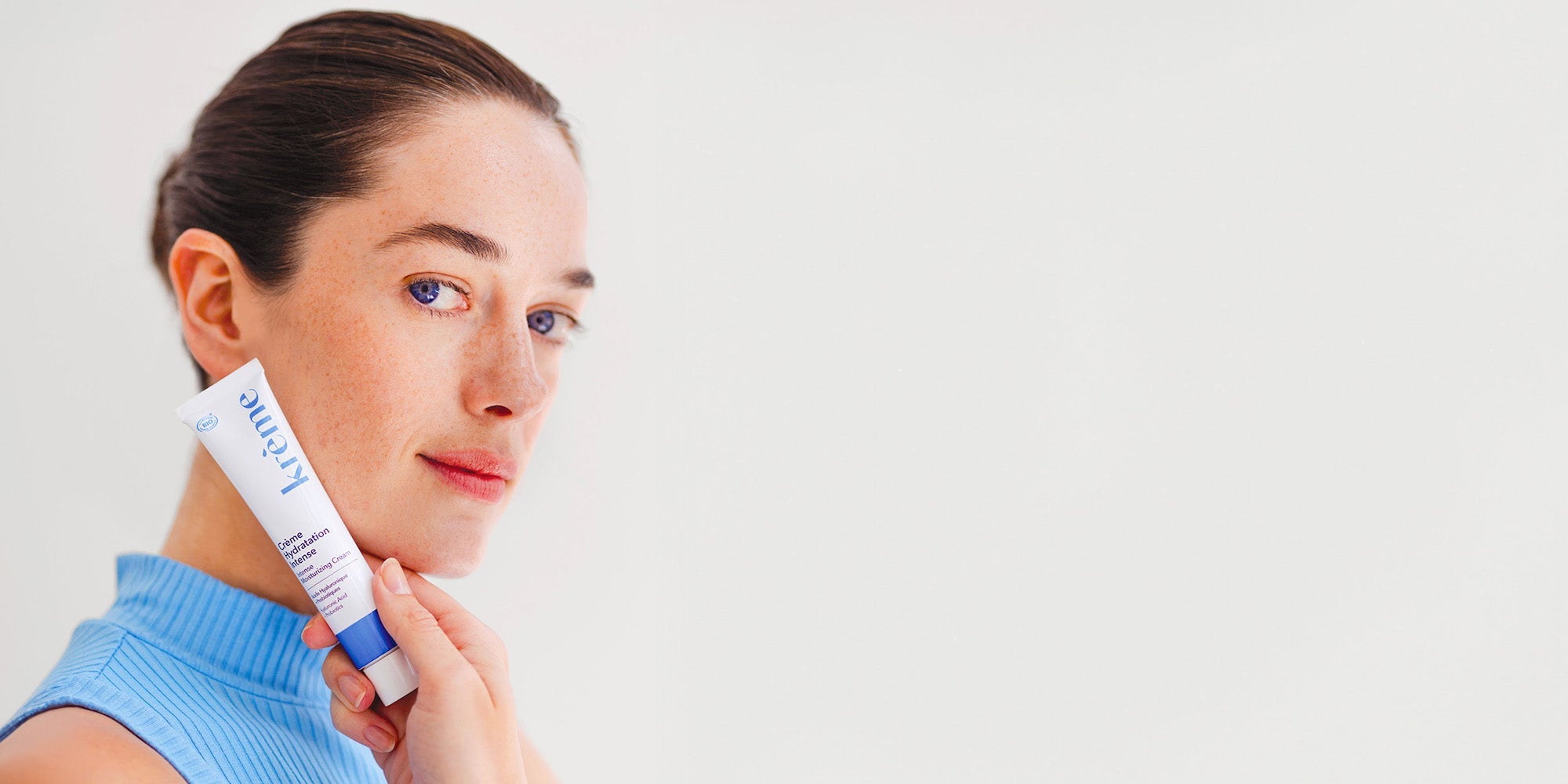 Femme qui montre une crème hydratante à l'acide hyaluronique