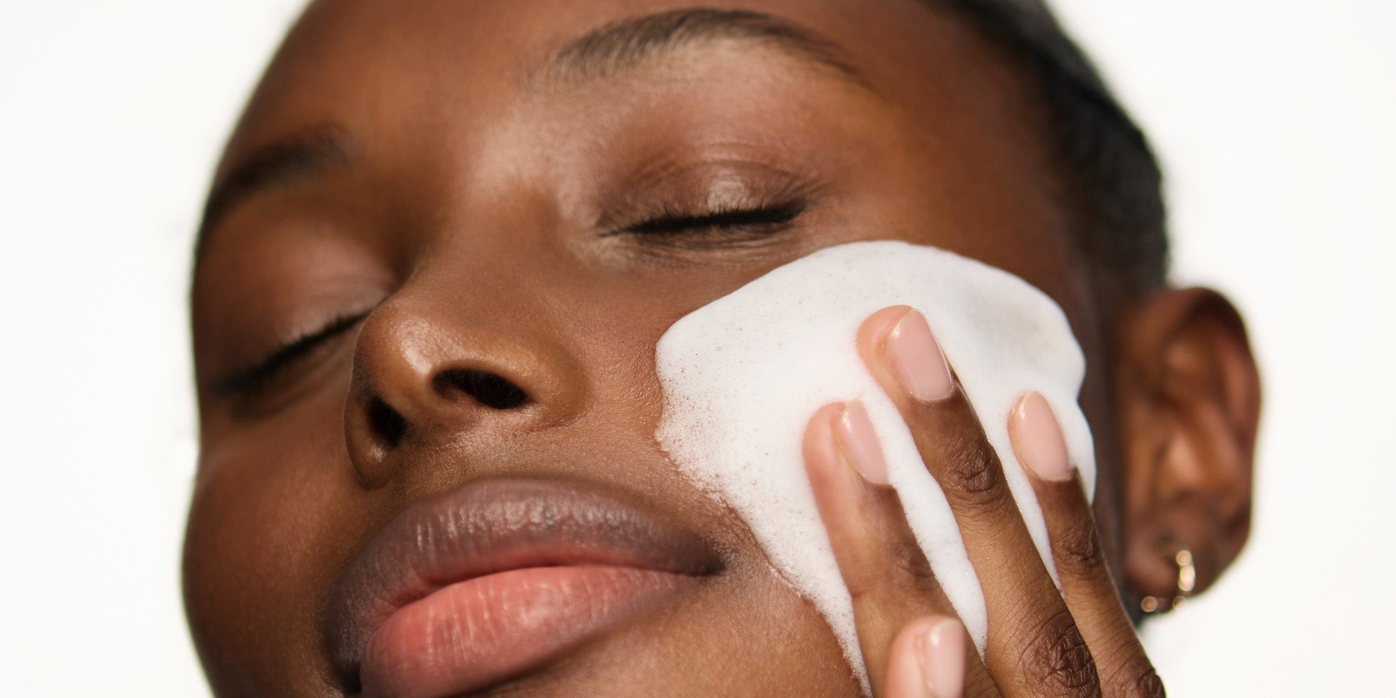 Femme qui applique une mousse nettoyante pour peau sensible